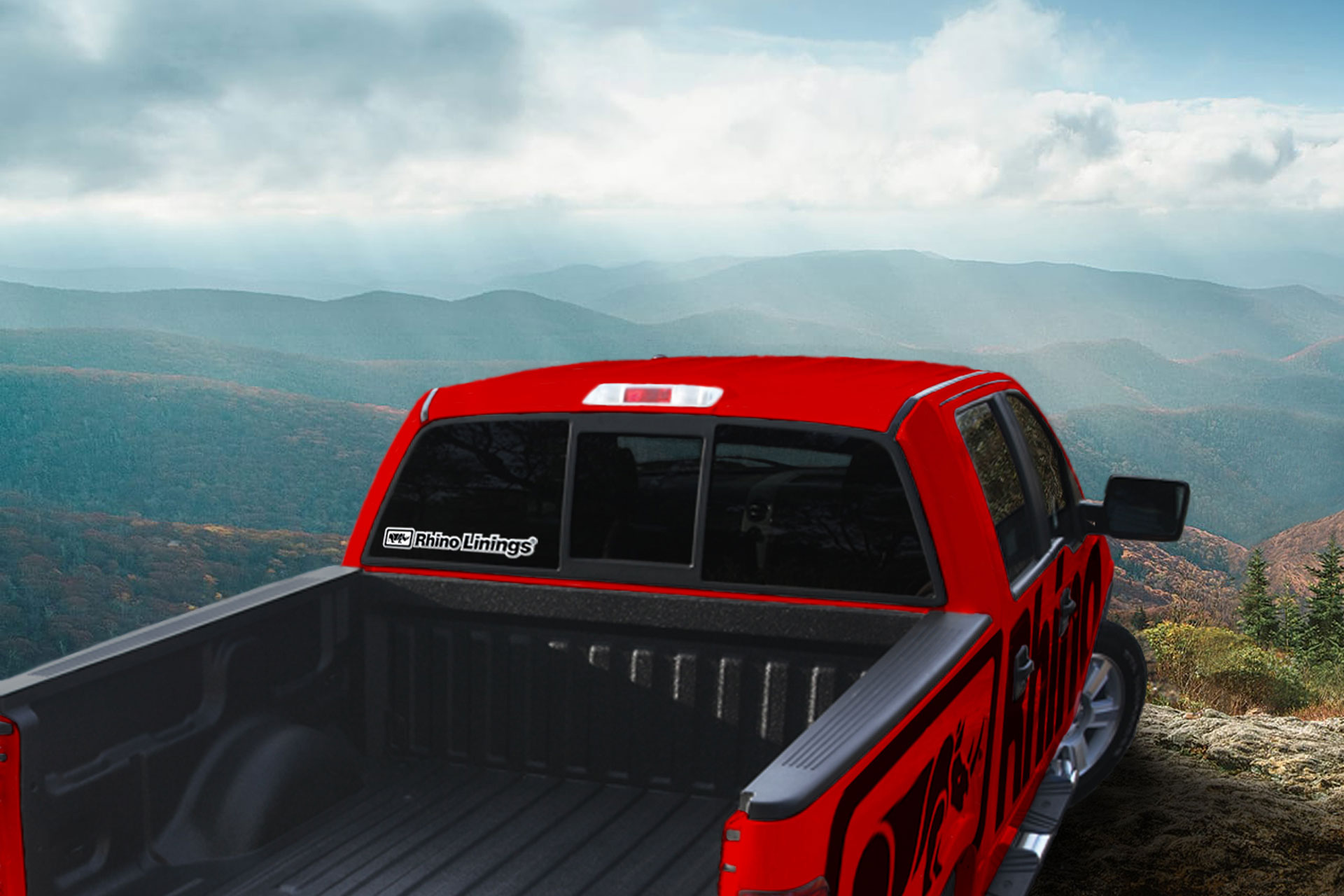 Red pickup truck with Rhino Linings branding parked atop of mountain with scenic view below